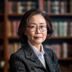 李明华教授头像，女性学者，戴眼镜，书架背景，学术气质浓厚